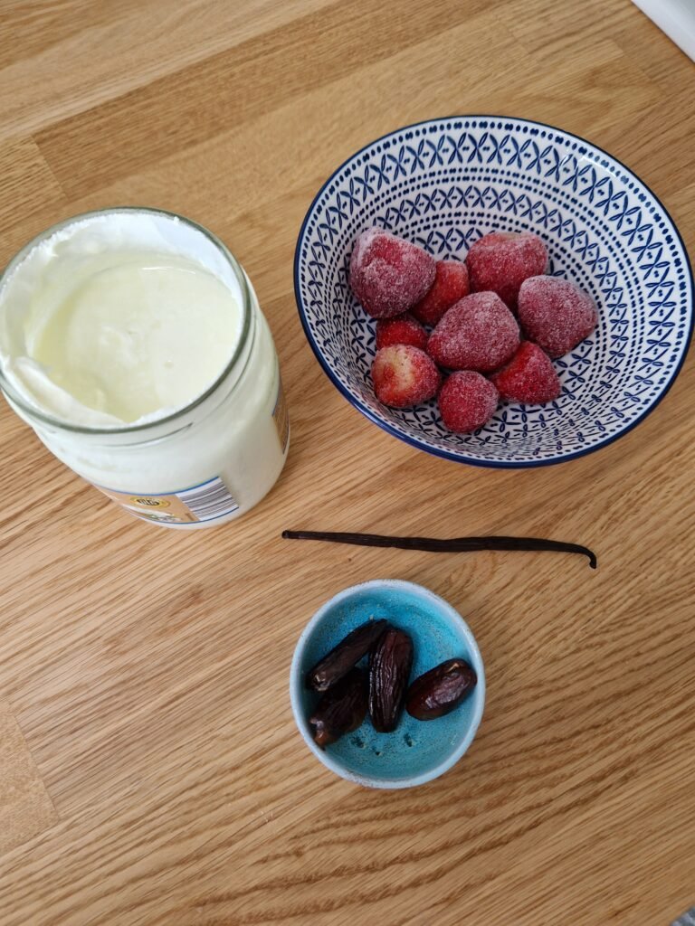 Naturjoghurt Erdbeeren Vanille und Datteln auf einer Arbeitsfläche