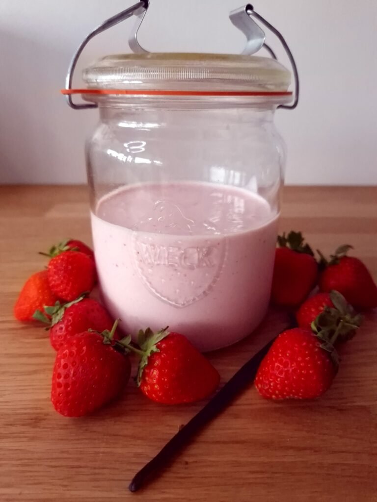 Erdbeerjoghurt in einem Glas mit Erdbeeren und Vanille auf einer Arbeitsfläche